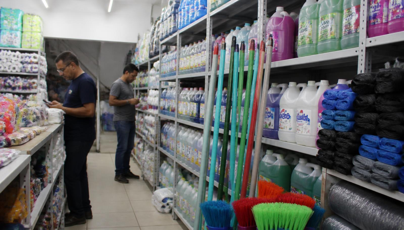 Corredor com produtos de limpeza, vassouras e detergentes